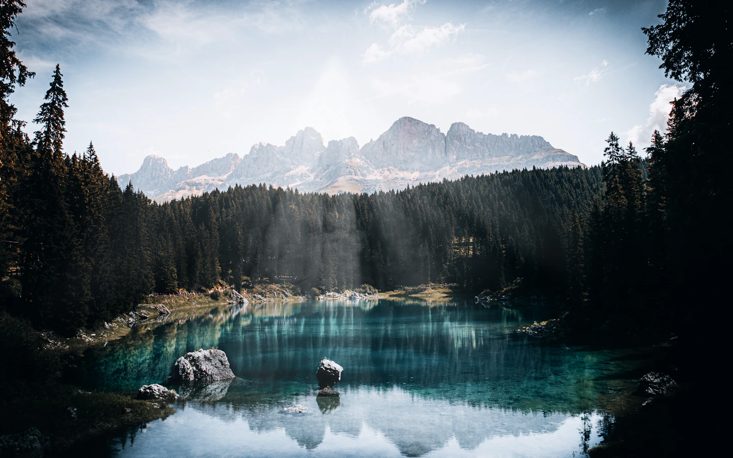 Evergreen trees and the Dolomites reflected in the turquoise water of Lake Carezza