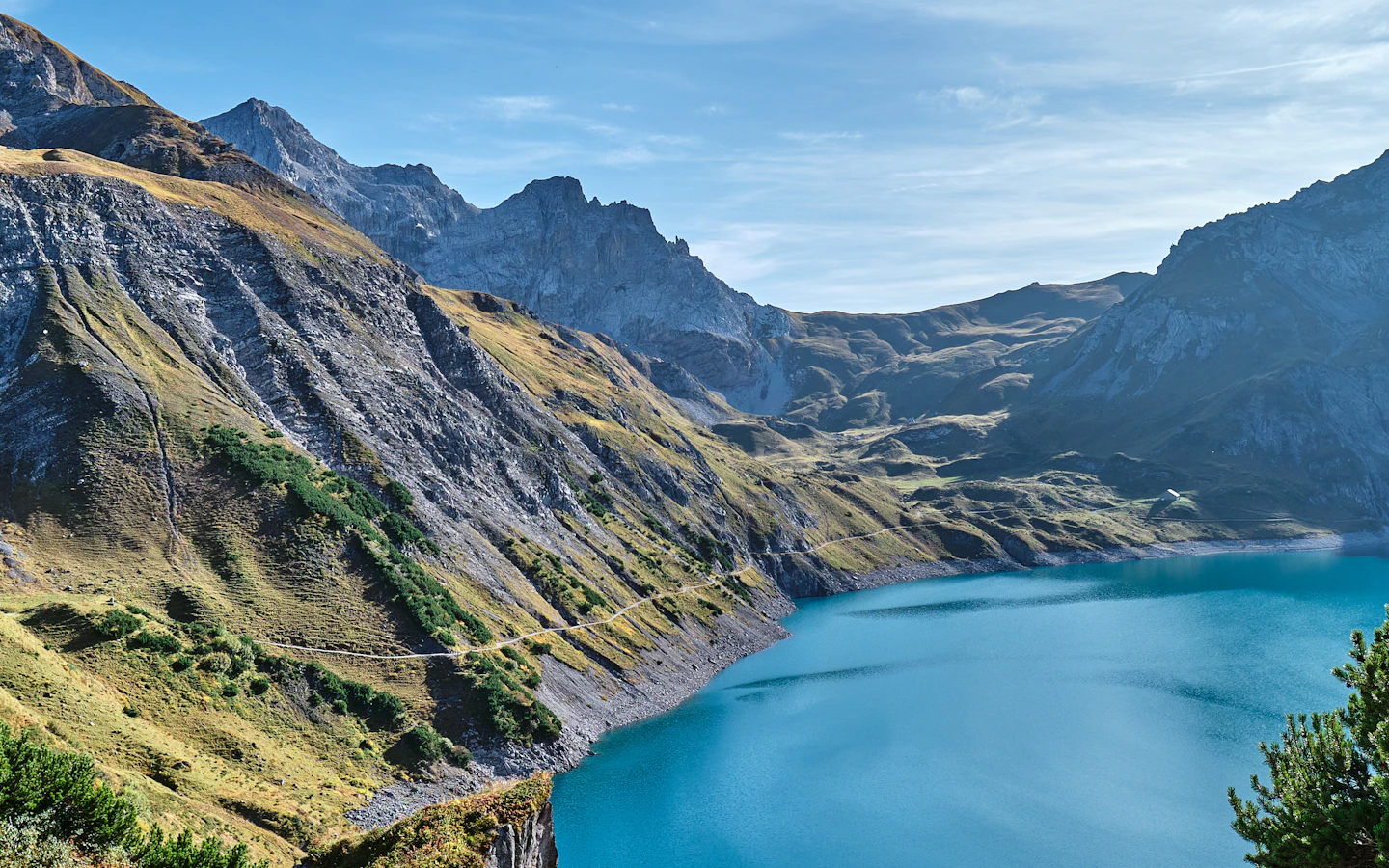 An alpine lake surrounded by steep rocky mountains under a blue sky